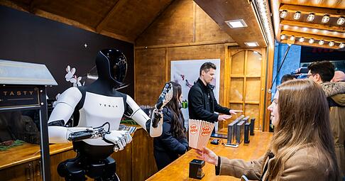 Der humanoide Roboter &laquo;Optimus&raquo; von Tesla verteilt bei seiner Vorstellung in der Mall of Berlin Popcorn an eine Besucherin.