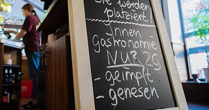Eine Tafel mit der Aufschrift «Innengastronomie - Nur 2G - geimpft - genesen» steht in einem Gasthaus.