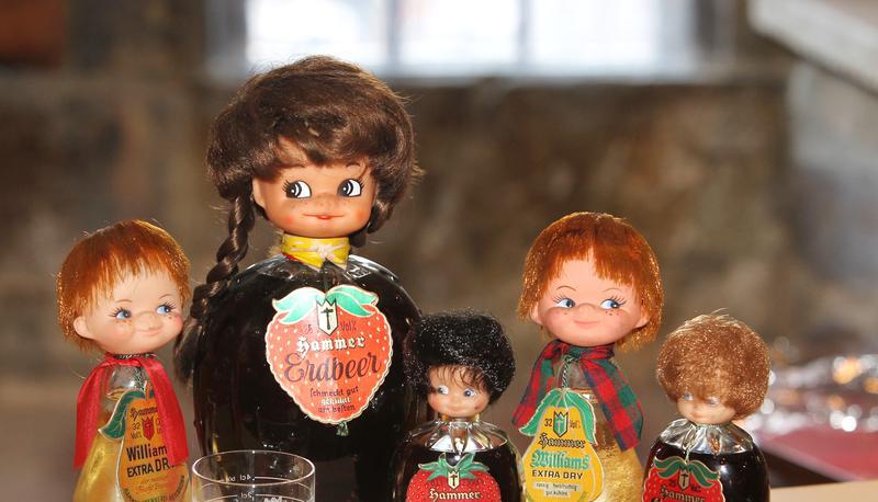 Puppenk&ouml;pfe zieren Lik&ouml;rflaschen in Birnen- und Erdbeerform.