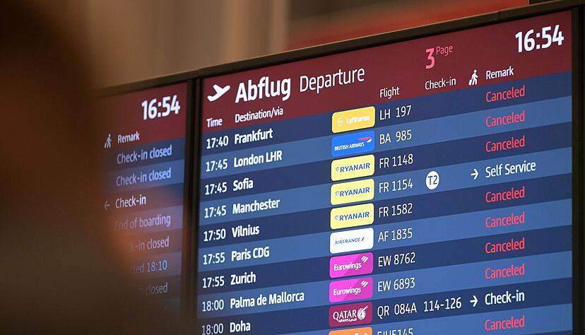 Passagiere blicken auf eine Anzeigetafel am Hauptstadtflughafen BER.