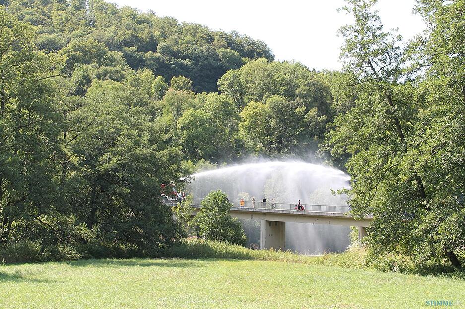 Die Feuerwehr spritzt von der Bächlinger Brücke Wasser in die Jagst