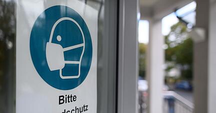 Ein Schild weist an der Tür eines Krankenhauses in Dresden auf die Maskenpflicht hin.
