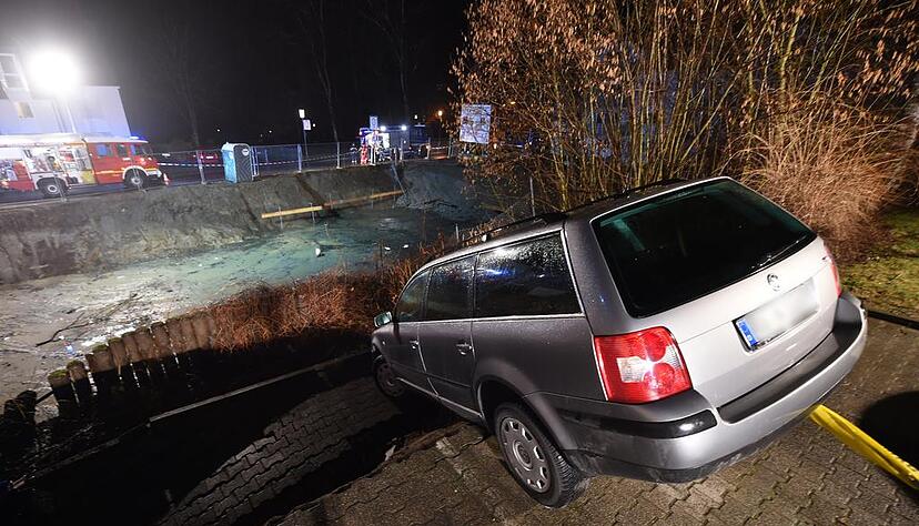 Durch einen Erdrutsch hängt ein Auto am 21.03.2015 in Weingarten (Baden-Württemberg) am Rand einer Baugrube. Damit das Auto nicht abrutscht, hat es die Feuerwehr mit einem Seil an einem Laster gesichert. Foto: Felix Kästle/dpa