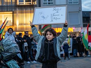 Ein Kind h&auml;lt ein Plakat mit dem Satz &bdquo;Rettet die Frauen in Rojava&ldquo; auf dem Heilbronner Kiliansplatz nach oben.