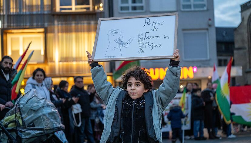 Ein Kind h&auml;lt ein Plakat mit dem Satz &bdquo;Rettet die Frauen in Rojava&ldquo; auf dem Heilbronner Kiliansplatz nach oben.