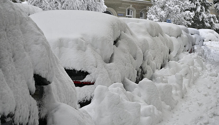 Eine dicke Schneeschicht liegt auf parkenden Autos.
