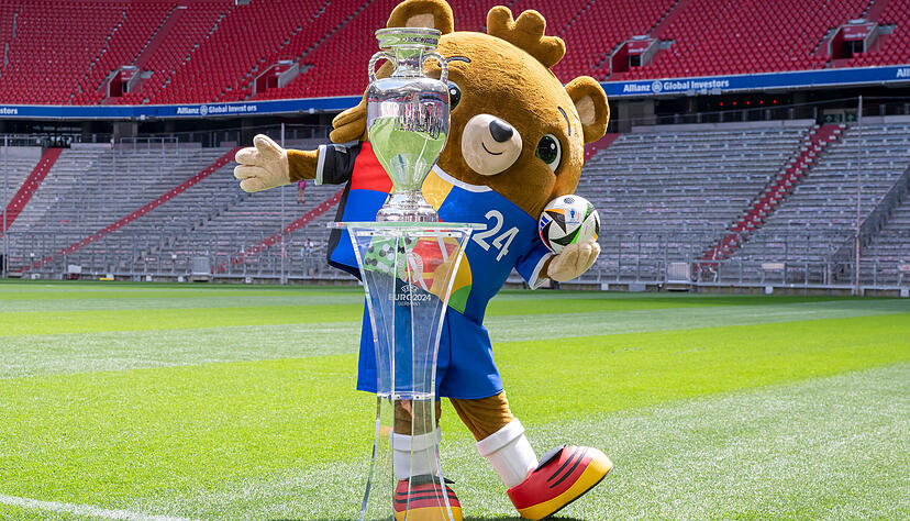 Albärt, Maskottchen der Fußball-EM 2024, präsentiert die Trophäe um die die 24 Teilnehmer spielen.