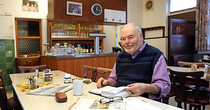 Ein Becher Kaffee, eine Scheibe Brot und das dicke Reservierungsbuch immer griffbereit: Sein Frühstück mitten im Lokal, ein bisschen Zeit nur für sich, das genießt Lothar Hesser. Foto: Andreas Veigel