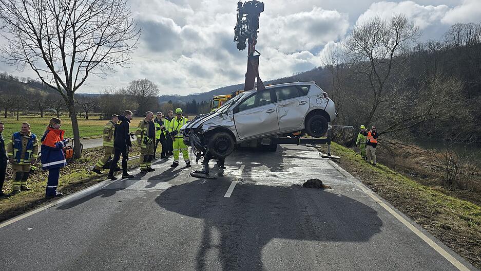 Um kurz nach 12 Uhr ist die Bergung des Toyota größtenteils beendet. Am Stahlseil eines Krans schwebt der Wagen aus der Jagst über das Ufer und wird zunächst auf der B19 abgesetzt.