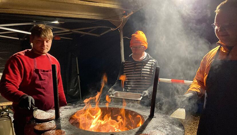 Einen warmen Arbeitsplatz haben die Helfer vom Weingut Borth. Sie wenden die Bratwurstscheiben für die Bratwurstburger am Holzgrill.