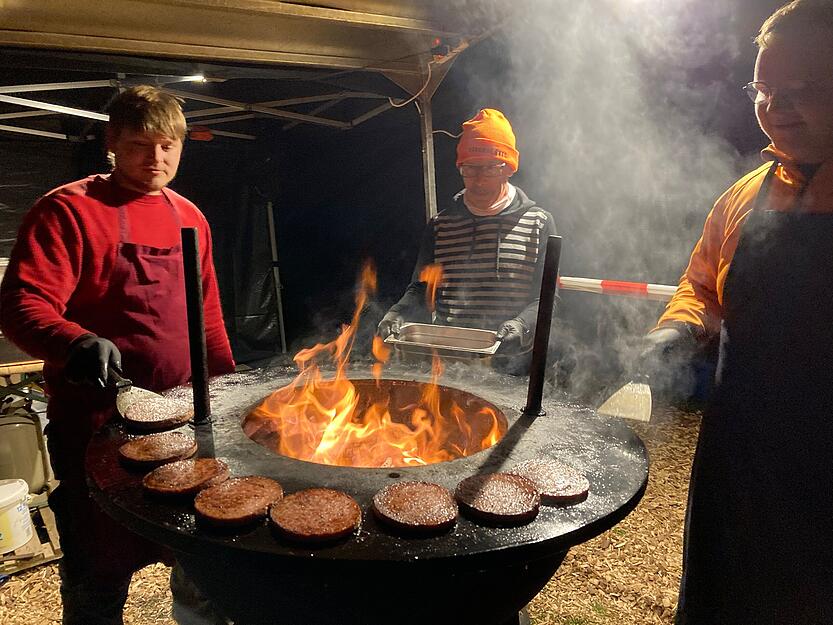 Einen warmen Arbeitsplatz haben die Helfer vom Weingut Borth. Sie wenden die Bratwurstscheiben für die Bratwurstburger am Holzgrill.