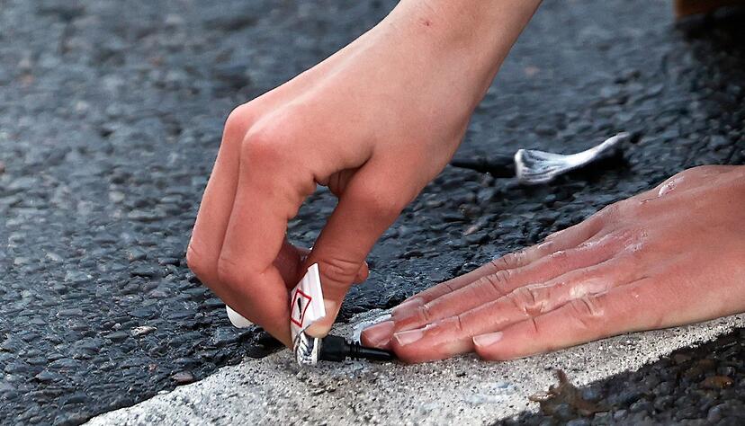 Ein Demonstrant klebt seine Hand in Berlin mit Sekundenkleber auf der Straße fest.