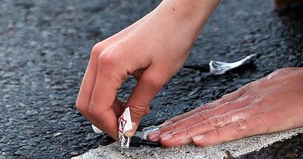Ein Demonstrant klebt seine Hand in Berlin mit Sekundenkleber auf der Straße fest.