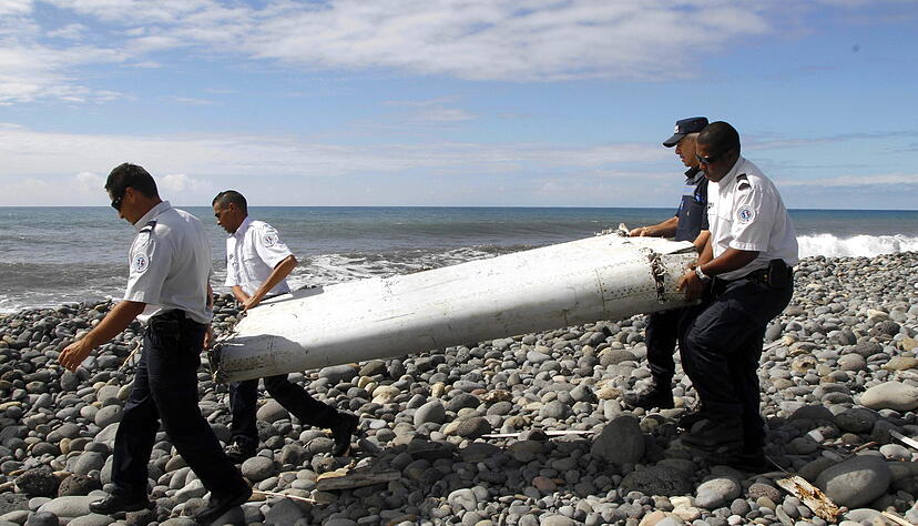 Techniker tragen ein Wrackteil, die Flügelklappe des Flugzeugs vom Flug MH370, über einen Strand bei Saint-Andre de la Reunion.