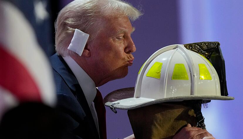 dpatopbilder - 18.07.2024, USA, Milwaukee: Der republikanische Präsidentschaftskandidat und ehemalige US-Präsident Donald Trump küsst den Helm von Corey Comperatore während der Republican National Convention. Foto: Matt Rourke/AP/dpa +++ dpa-Bildfunk +++