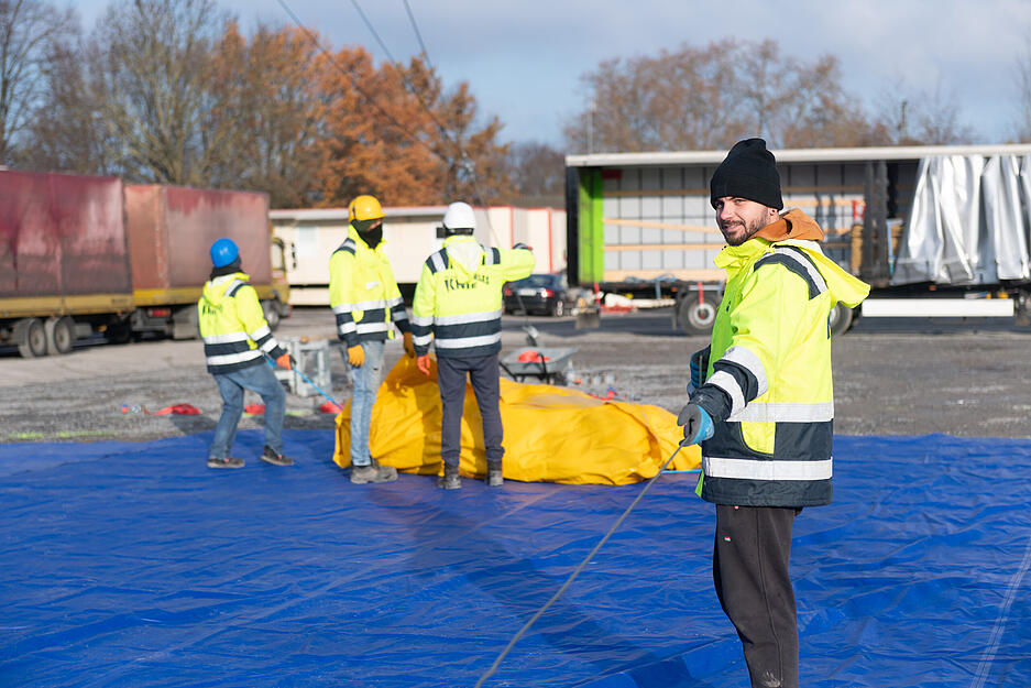 Techniker sichern die Stahlseile und Stützen des Rundzelts.