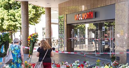 Trauerkerzen und Blumen liegen vor dem Kaufhaus, in dem der Täter Menschen mit einem Messer attackiert hatte.