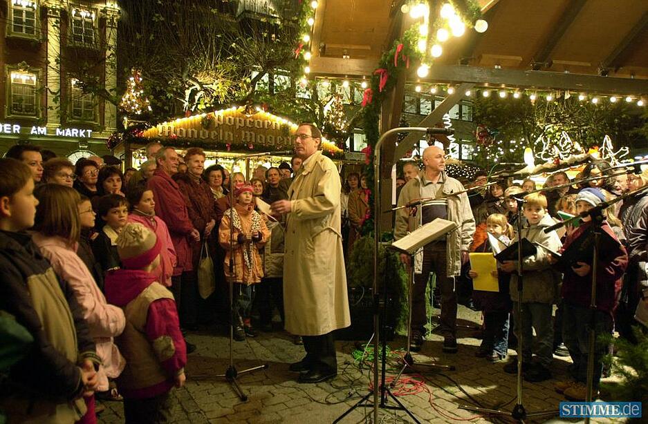 Aufmerksame kleine Zuhörer lauschen den Worten von OB Helmut Himmelsbach bei der Eröffnung des Weihnachtsmarkts auf dem festlich beleuchteten Heilbronner Marktplatz 2002.