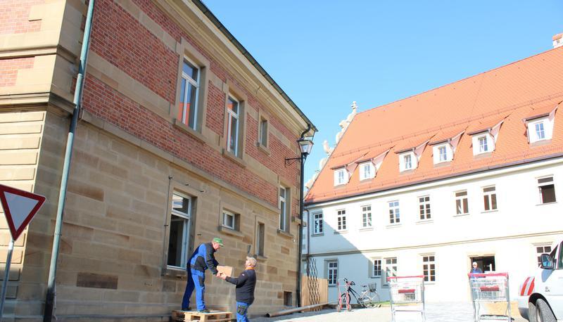 Bauhofmitarbeiter tragen die K&ouml;rbe und Kisten voller Akten, Dokumente und Unterlagen &uuml;ber den Hof ins Schl&ouml;ssle nebenan.