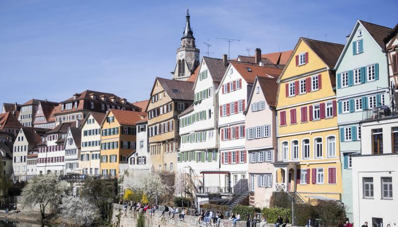 Einige Menschen sitzen auf der Neckarmauer in der T&uuml;binger Innenstadt.