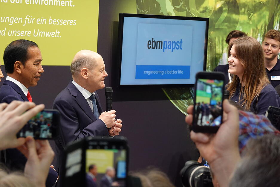 Bundeskanzler Olaf Scholz und Indonesiens Staatspr&auml;siedent Joko Widodo lassen sich von EBM-Papst-Studentin Melanie Bildhoff erl&auml;utern, was das Besondere an den Kompressoren ist.