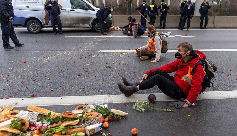 Klimaaktivisten der Gruppe &laquo;Aufstand der letzten Generation&raquo; sitzen auf der Fahrbahn und blockieren den Verkehr.