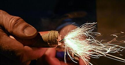 Ein Mann zündet einen Böller am Silvesterabend an.