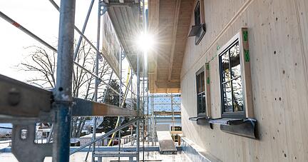 Die Sonne scheint zwischen einem Ger&uuml;st und einem Neubau hindurch.