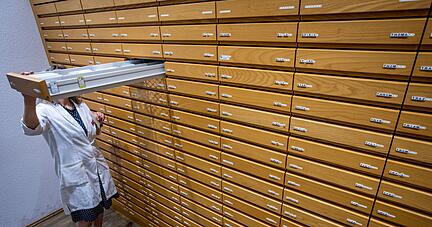 Eine Mitarbeiterin sucht rezeptpflichtige Medikamente aus einem Apothekenschrank.