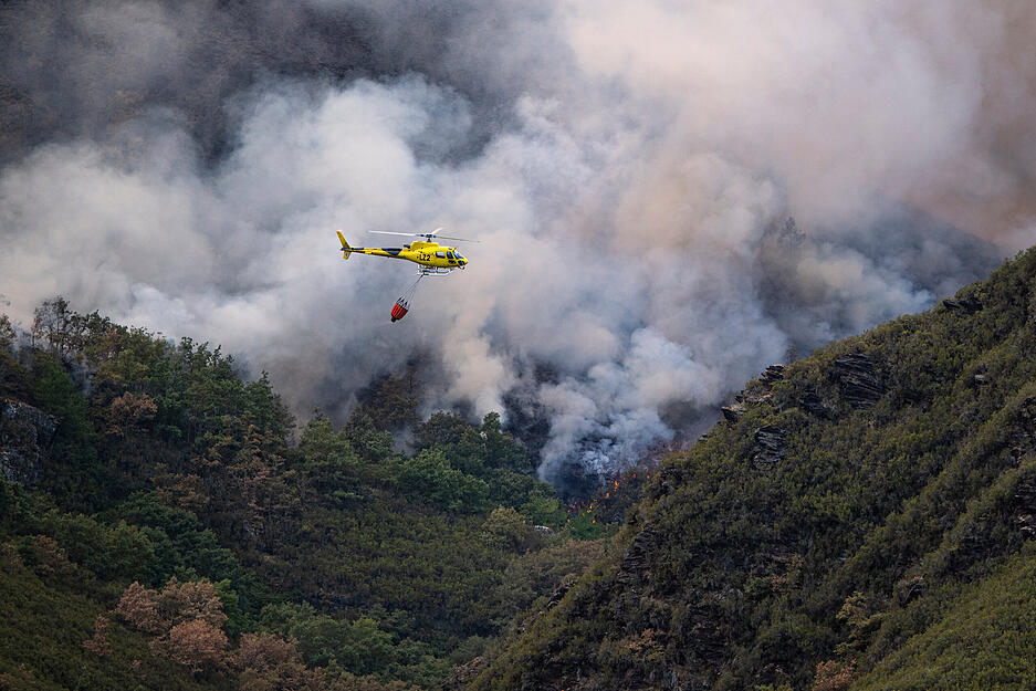 Mitglieder der milit&auml;rischen Notfalleinheit bei den L&ouml;scharbeiten mit einem Helikopter des Villarub&iacute;n-Brandes in Spanien.