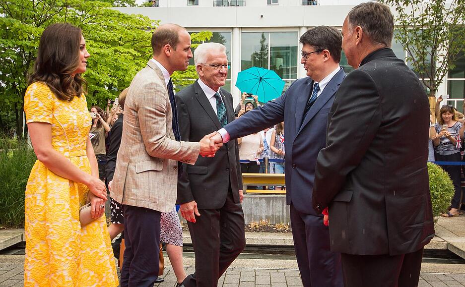 Der britische Prinz William (2.v.l.) und seine Frau Herzogin Kate (l) erreichen das Deutsche Krebsforschungszentrum in Heidelberg und werden dort von Baden-Württembergs Ministerpräsident Winfried Kretschmann (3.v.l., Bündnis 90/Die Grünen), Michael Baumann, Vorstand Wissenschaft des dkfz (4.v.l.) und Josef Puchta, Kaufmännischer Vorstand des dkfz begrüßt.