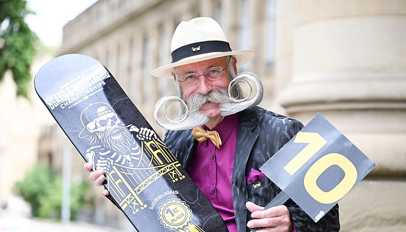 Er pr&auml;sentiert seine Siegertroph&auml;e und eine Wertungstafel mit der Maximalpunktzahl 10.