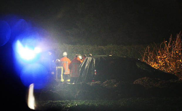 Rettungskr&auml;fte der Feuerwehr stehen in der N&auml;he der Unfallstelle neben Enkes schwarzen Mercedes Gel&auml;ndewagen.
