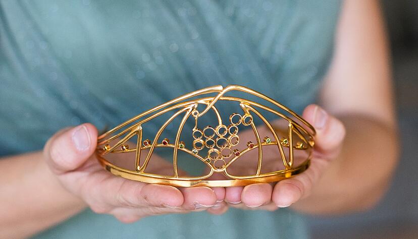 Eine Frau h&auml;lt die Krone einer Weink&ouml;nigin in den H&auml;nden.