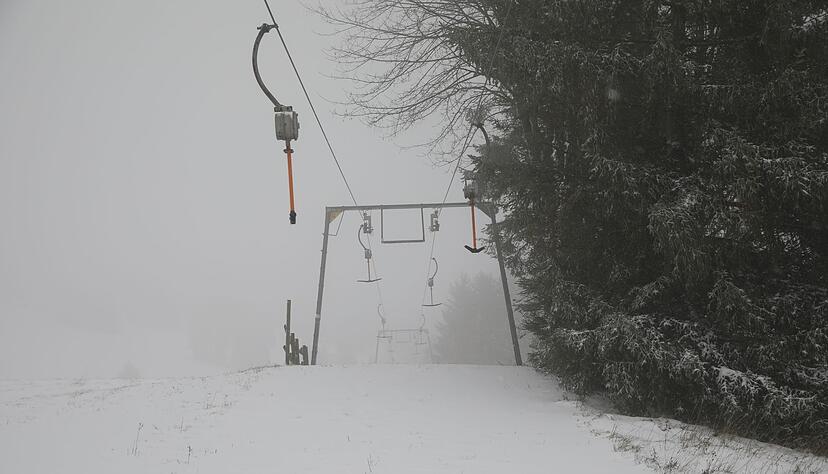 Ein stehender Skilift mit einer verschneiten Skipiste