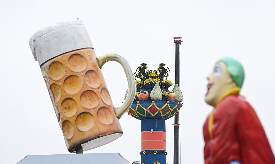 Die Fruchtsäule, das Symbol des Volksfestes auf dem Wasen, wird umrahmt von einem überdimensionalen Bierkrug und einer Figur an einem Geschäft auf dem Festareal bei Bad Cannstatt.
