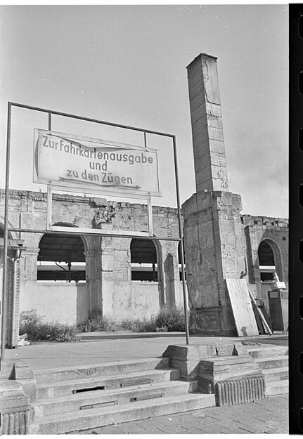 Aus den Trümmern des Heilbronner Hauptbahnhofes weist das Schild  zum provisorischen Bahnschalter, der bis ins Ende der 1950er Jahre hinein in Betrieb ist.