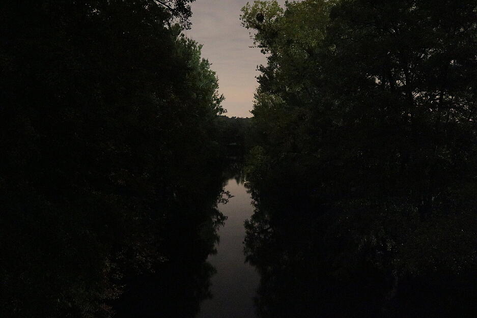 Wetterleuchten spiegeln sich in der Jagst bei Kloster Schöntal. Der Fluss wirkt sehr ruhig, weil die Wellen durch die lange Belichtungszeit verwischt werden.