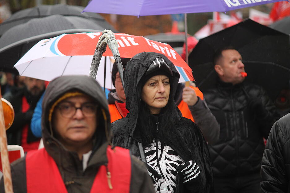 Zahlreiche Menschen versammeln sich trotz schlechten Wetters zum Protest.