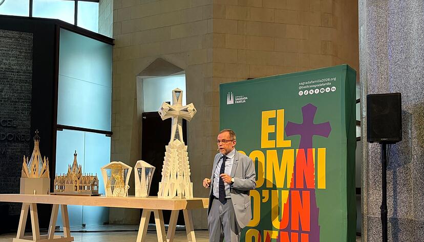 Der leitende Architekt der Sagrada Familia, Jordi Faulí, erklärt vor einem großen Poster den Aufbau des großen Kreuzes aus Deutschland für den Hauptturm der Basilika.