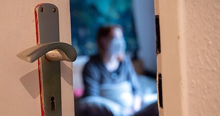 Eine Frau sitzt während der Isolation nach einem positiven Corona-PCR-Test auf ihrem Bett. Eine Frau sitzt während der Isolation nach einem positiven Corona-PCR-Test auf ihrem Bett.