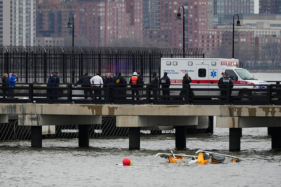 Ersthelfer stehen an der Stelle, an der der Hubschrauber in den Hudson River gestürzt ist. Für die Insassen des Helikopters kam jede Hilfe zu spät.