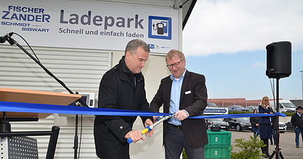 Bürgermeister Uwe Mosthaf (links) und Fischer-Zander Geschäftsführer Peter Crasser schneiden das Eröffnungsband für den neuen Ladepark durch.