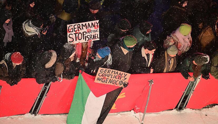 Zuschauer mit propal&auml;stinensischen Schildern am Rand des Teppichs.