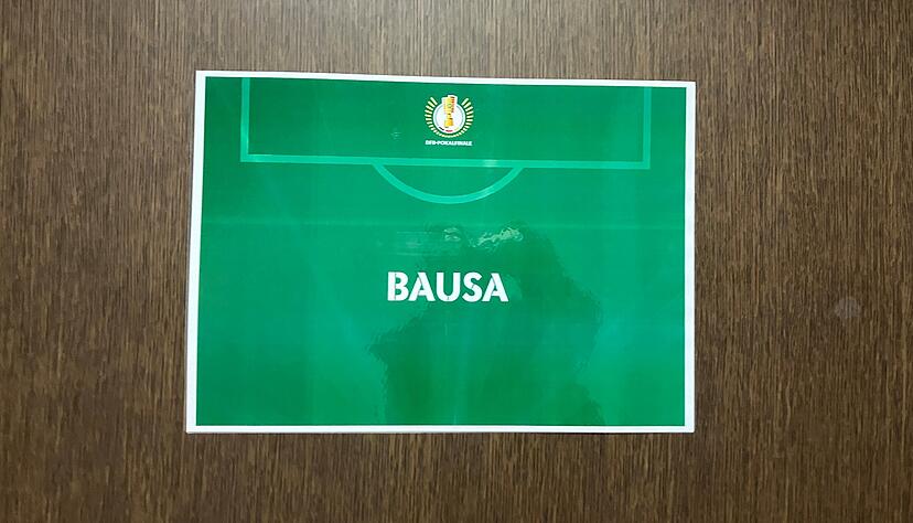 An einer Kabine in den Katakomben des Olympiastadions steht das Namensschild "Bausa". Tritt der Rapper beim DFB-Pokalfinale auf?