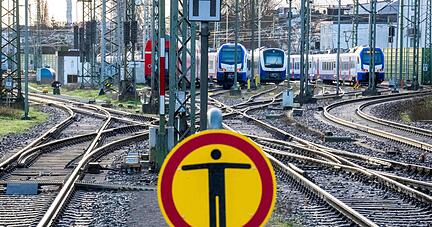 Abgestellte Z&uuml;ge auf den Gleisen vor einem Bahnhof.