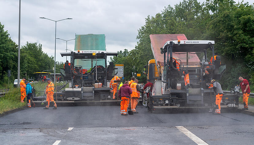 Unter Hochdruck bauen die Straßenarbeiter die erste Asphaltschicht auf der B 27 ein.