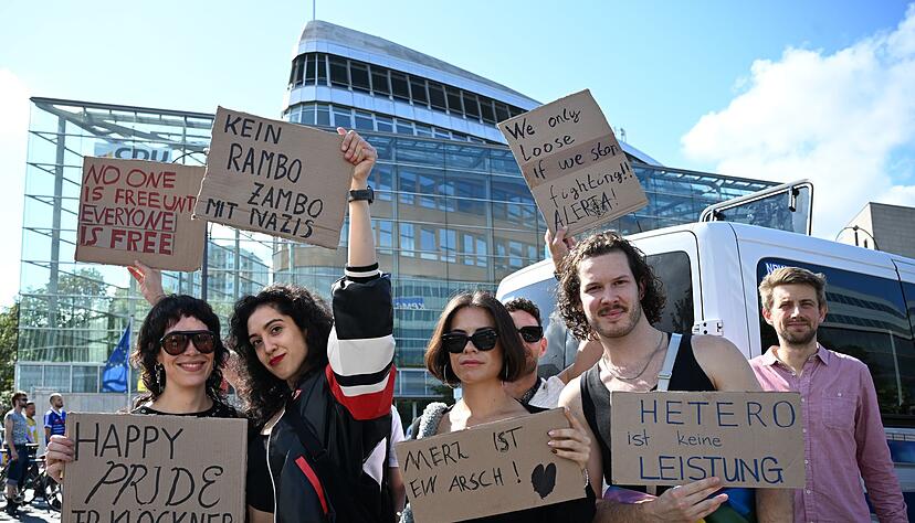 Teilnehmerinnen und Teilnehmer greifen auf ihren Plakaten auch die Kontroverse um die Regenbogenflagge am Bundestag auf.