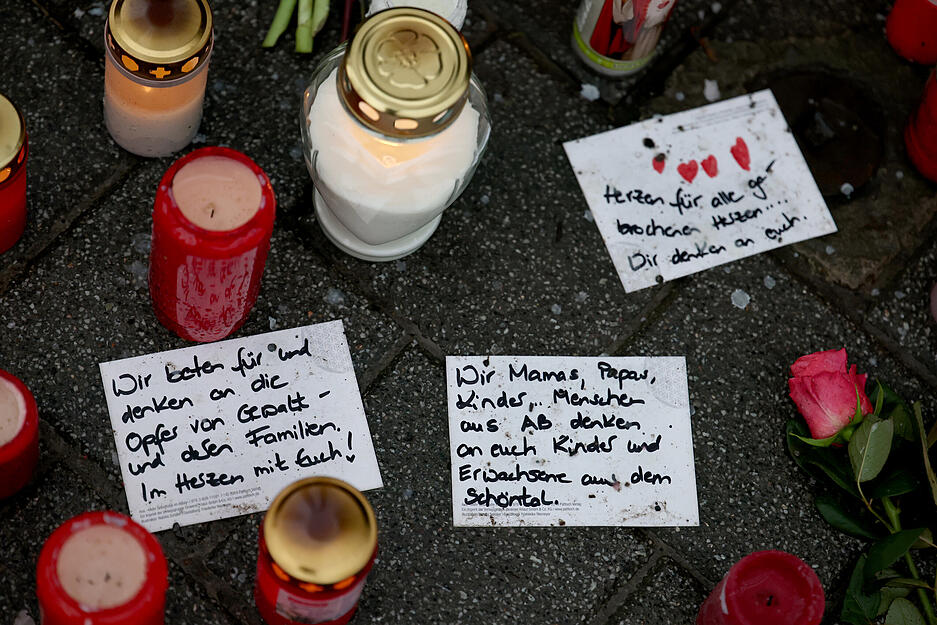 Handgeschriebene Trauerbekundungen liegen neben Trauerkerzen.