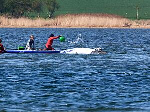 Der Buckelwal wird von Helfern vor der Insel Poel mit Wasser aus einer Gie&szlig;kanne bespritzt.